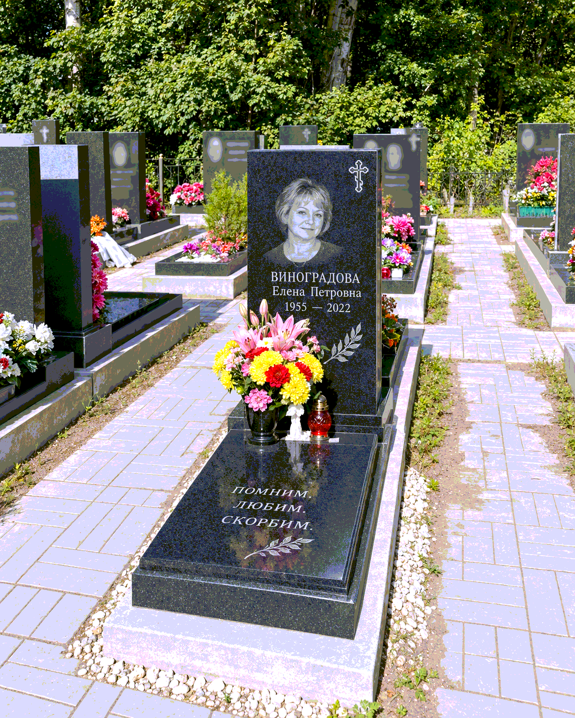 Закрытая плита с вазой и цветами после установки на участке. Имена, даты и портреты изменены.