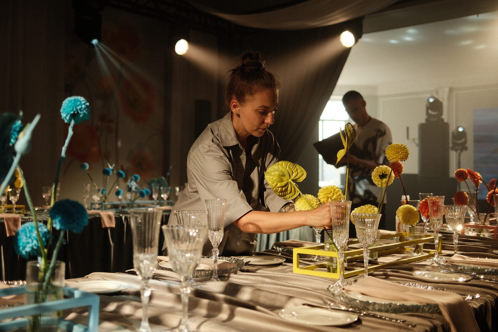 флорист работает с цветочными композициями на прямоугольных столах