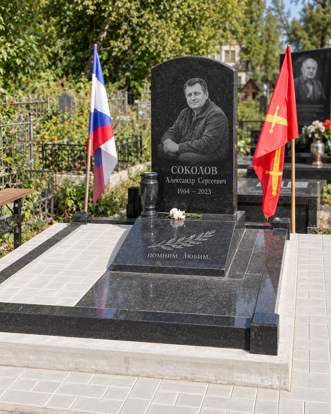 Памятник с надгробной плитой после установки на участке. Имена, даты и портреты изменены.