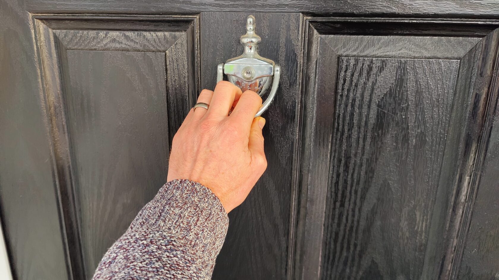 Hand knocking at the front door of a care home