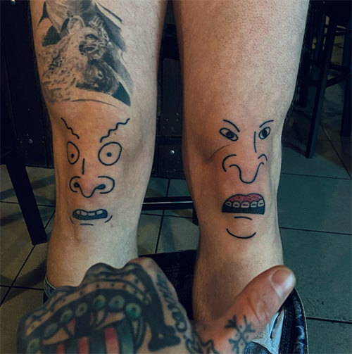 Paired knee tattoos featuring Beavis and Butt-Head. Minimalistic outline tattoos of the MTV cartoon characters, done in black lines on both legs. The work was done by artist Egor Leshchev.