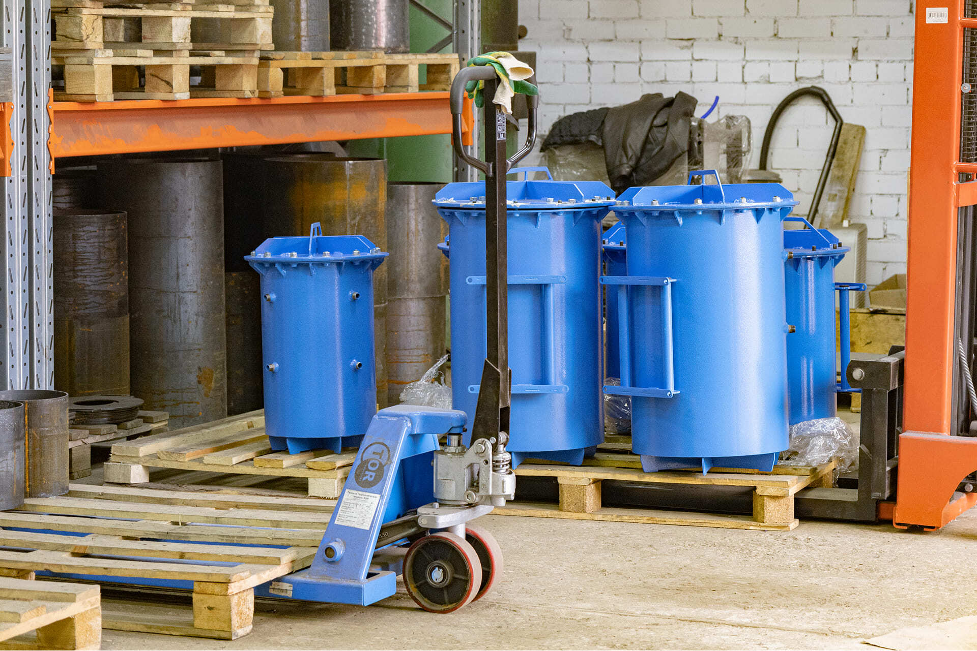 Готовые корпуса вакуумных камер синего цвета на поддонах в производственном цехе