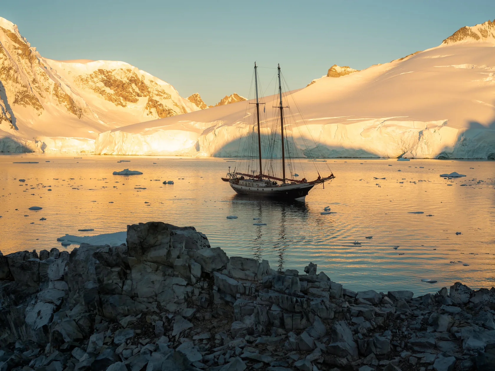 Sailing yacht surrounded by glaciers and floating ice during an Antarctica expedition along the Antarctic Peninsula.