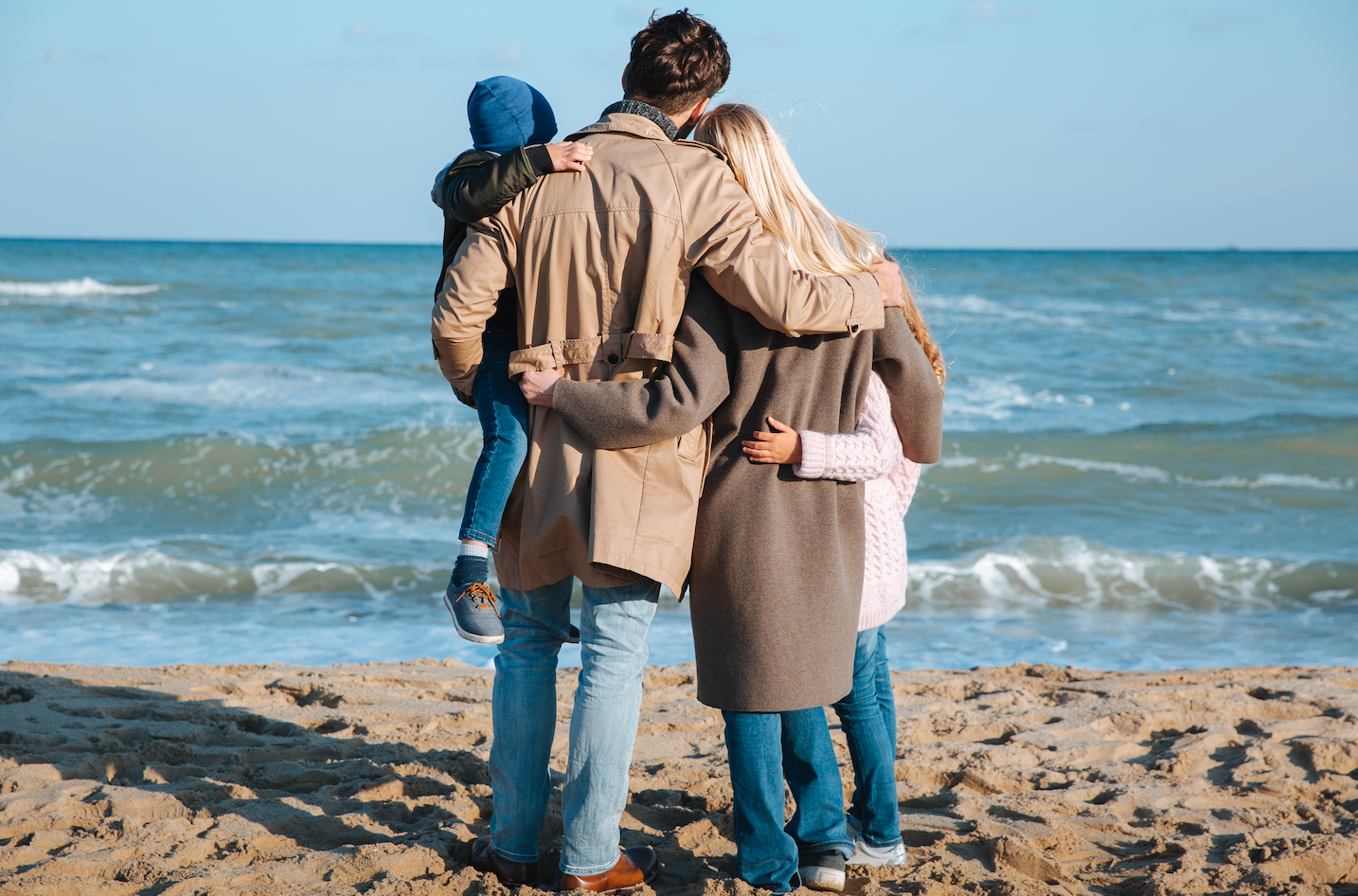 Папу с мамой берегу. Семейные объятия. Счастливая семья обнимается. Семейная фотосессия на берегу моря осенью. Семья на море со спины.