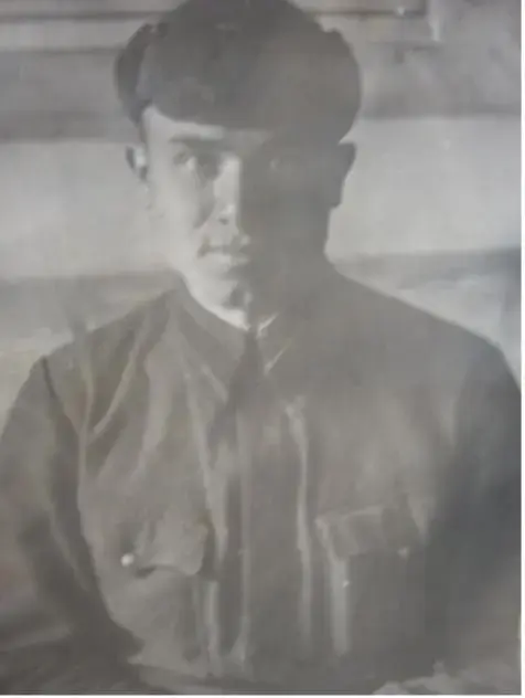 Расширенный alt: Архивная чёрно-белая фотография: молодой мужчина в военной форме сидит в помещении и смотрит в камеру; снимок слегка размытый, с мягким светом и следами времени.