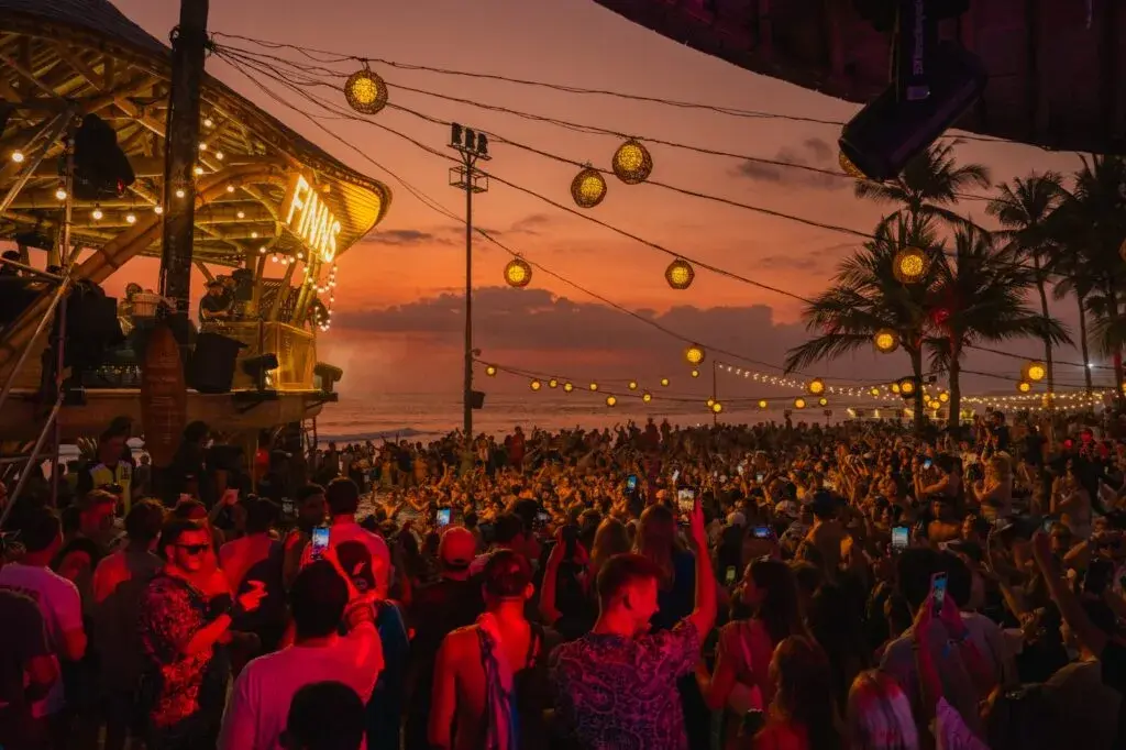 lively sunset crowd gathering at a beachfront club in Canggu to enjoy drinks and music, capturing the energetic vibe of what happens in Bali on Wednesday.