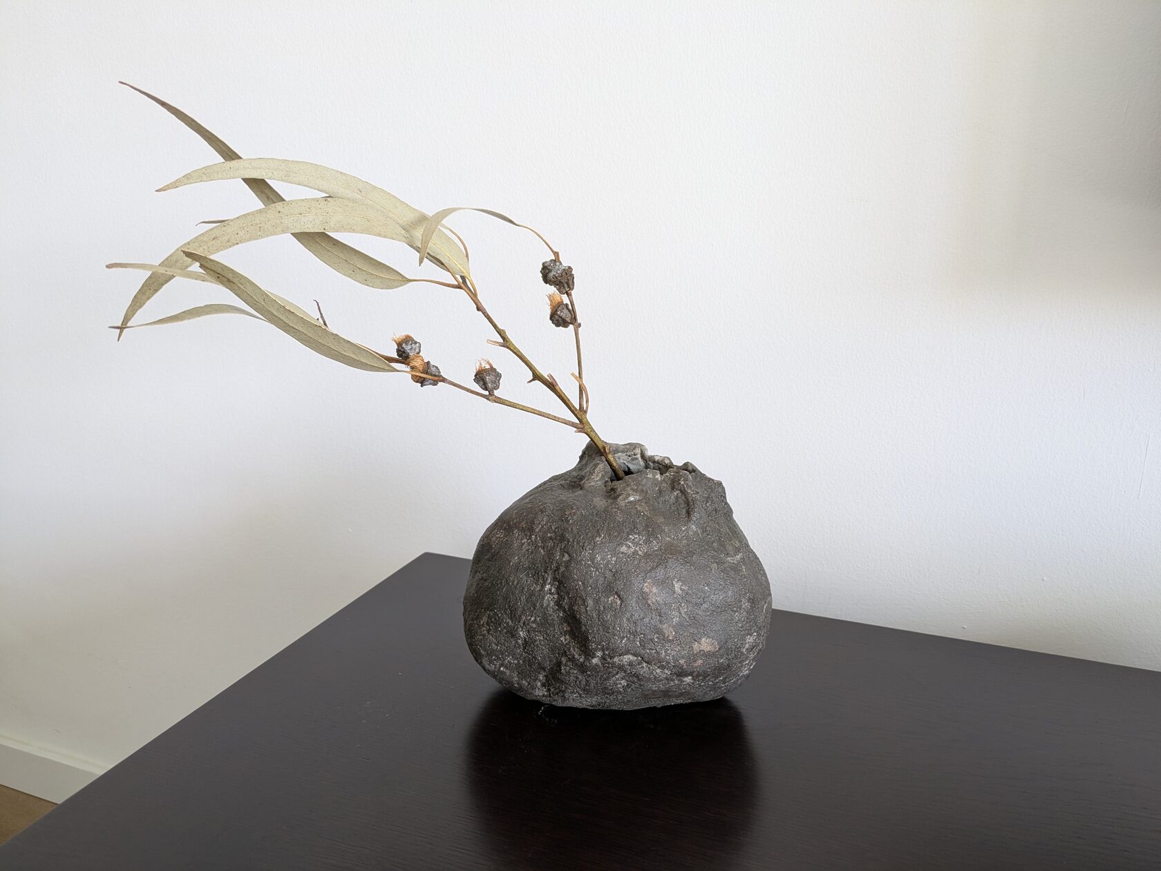 Asymmetrical decorative stone vase styled as a dining table centerpiece with soft neutral tones