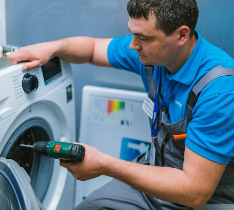 Мастер ремонтирует стиральную машину