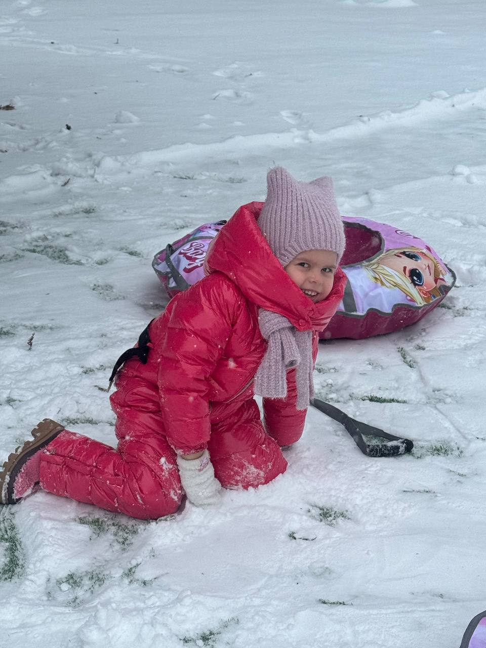 Девочка на прогулке катается на ватрушке с горки зимой