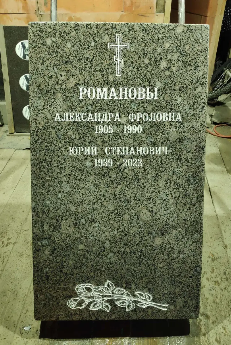 Серая стела после обновления оформления: две надписи, крест и гравировка роз внизу.