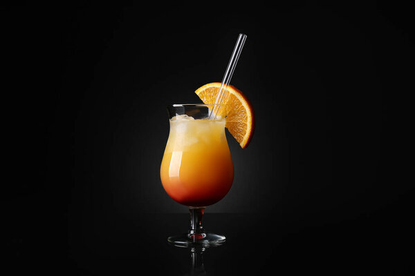 На черном фоне в стакане Харрикейн изображен коктейль Tequila Sunrise, который переходит градиентом от красного к оранжевому. В стакане видны кубики льда, украшенные долькой апельсина, и прозрачная трубочка.