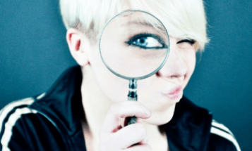 Девушка смотрит через лупу