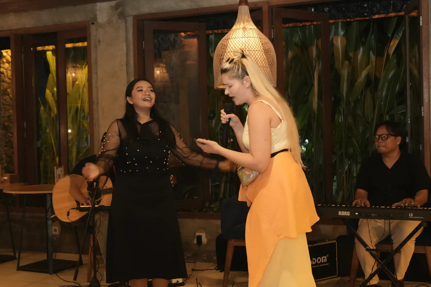 Two female singers having fun while performing a live acoustic music set for the evening guests.
