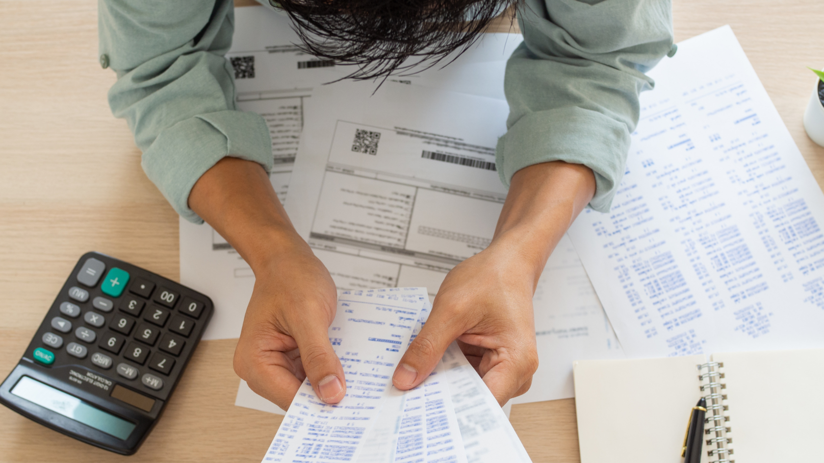 A professional reviewing documents of business expenses and earnings to assess EBITDA adjustments.