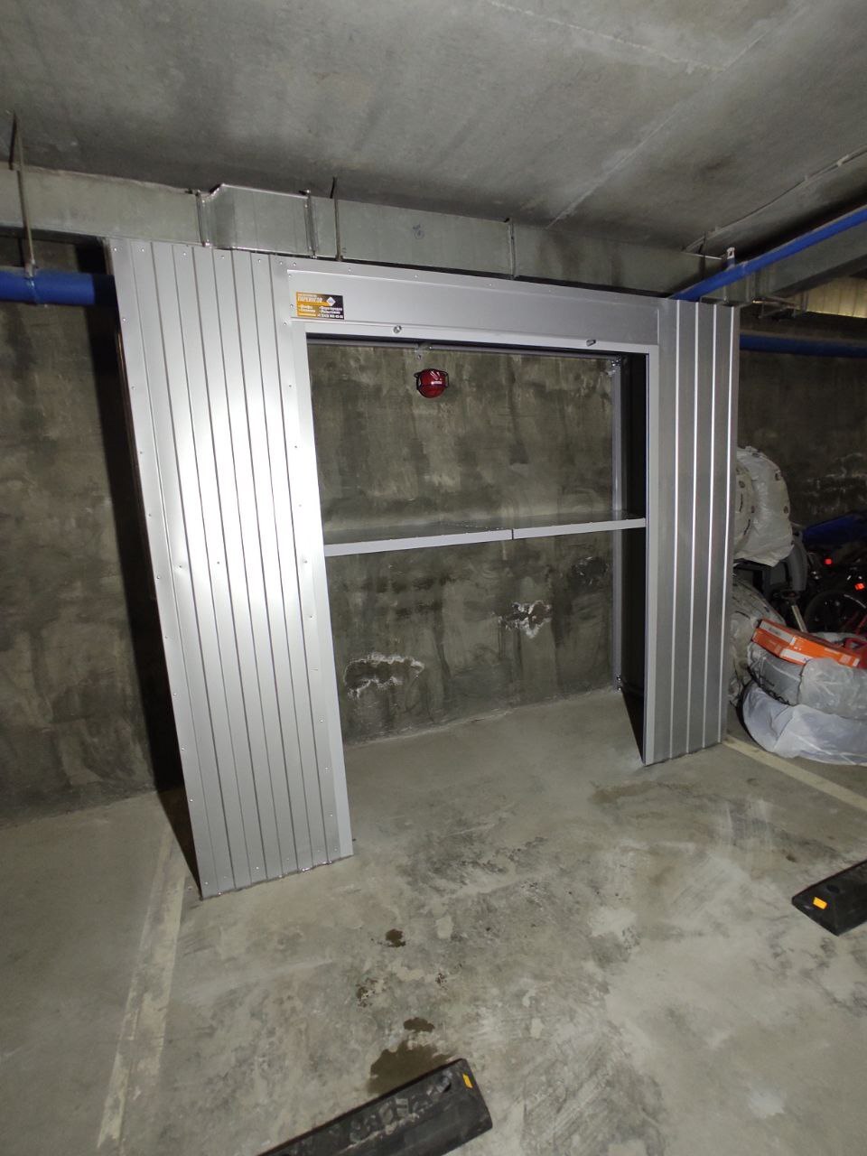 Роллетный шкаф-кладовая в паркинг (MaxParking) серебристого цвета из профлиста с металлическими полками для хранения шин, покрышек