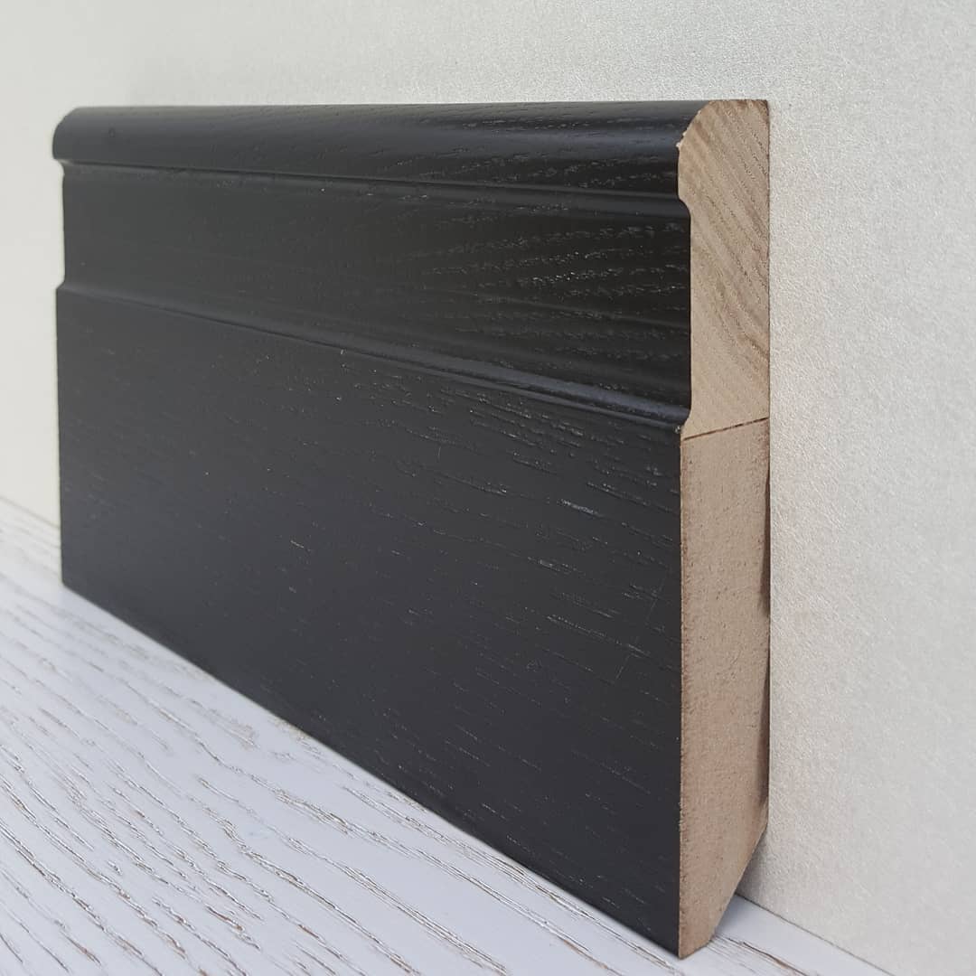 Темный плинтус из массива, контрастирующий с белыми стенами.