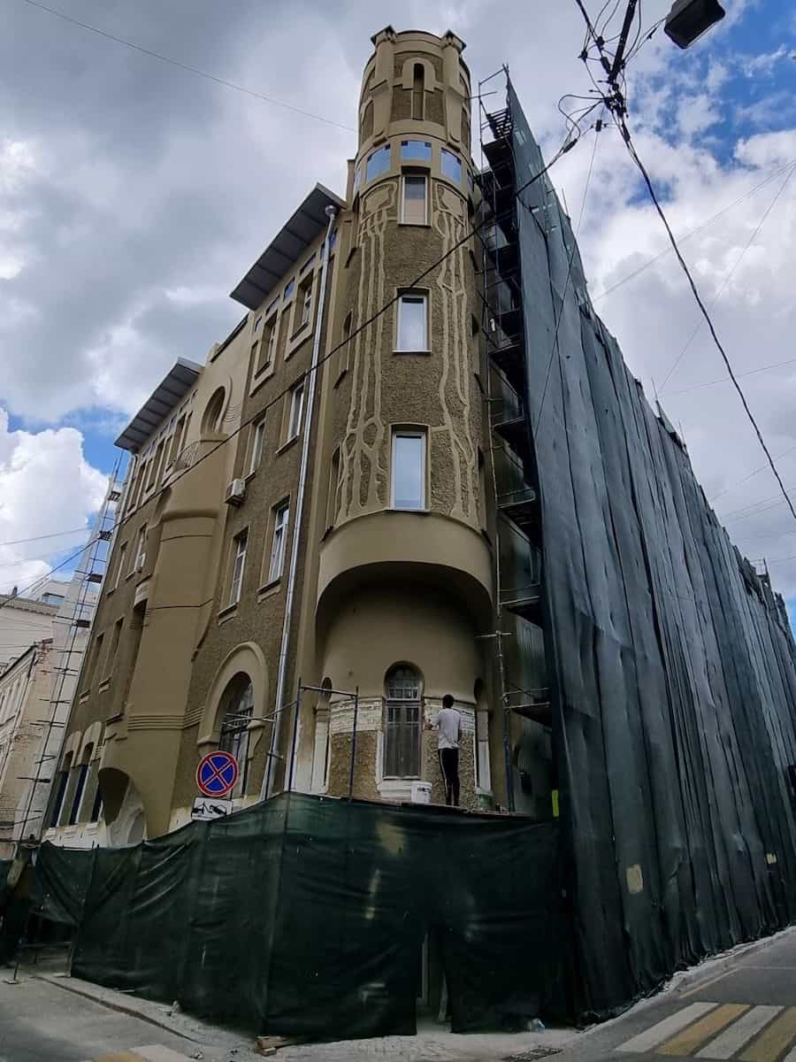 Угловой дом с башней и строительной сеткой