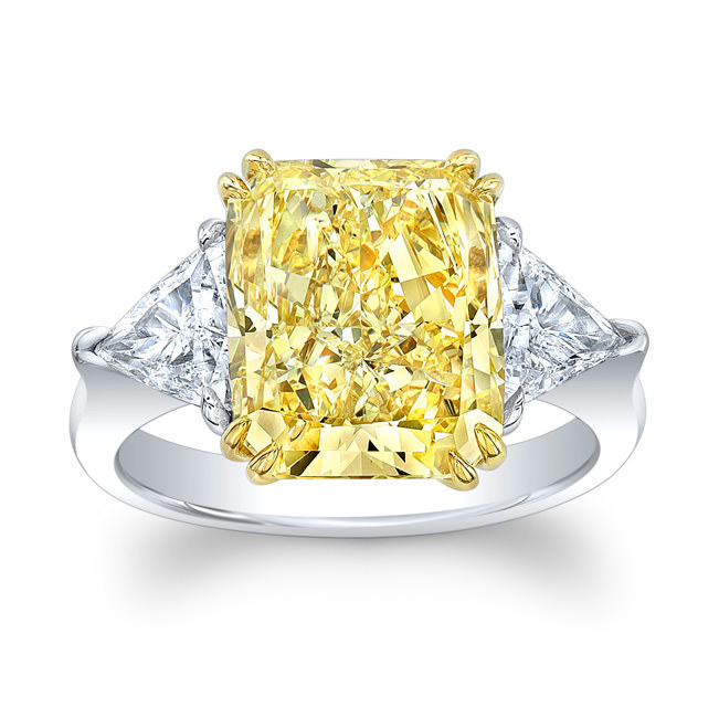 Кольцо с фантазийным желтым бриллиантом огранки радиант и двумя белыми бриллиантами огранки триллион по бокам.