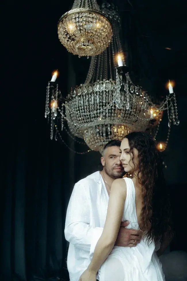 Пара обнимается под хрустальными люстрами во время фотосессии Love Story в студии