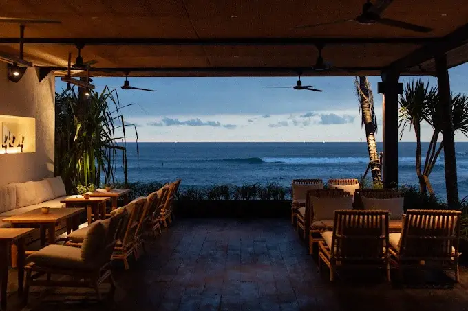 A serene ocean view from the chic, warmly lit wooden deck at The Lawn Canggu, easily one of the best bars in Bali for an elegant sunset session.