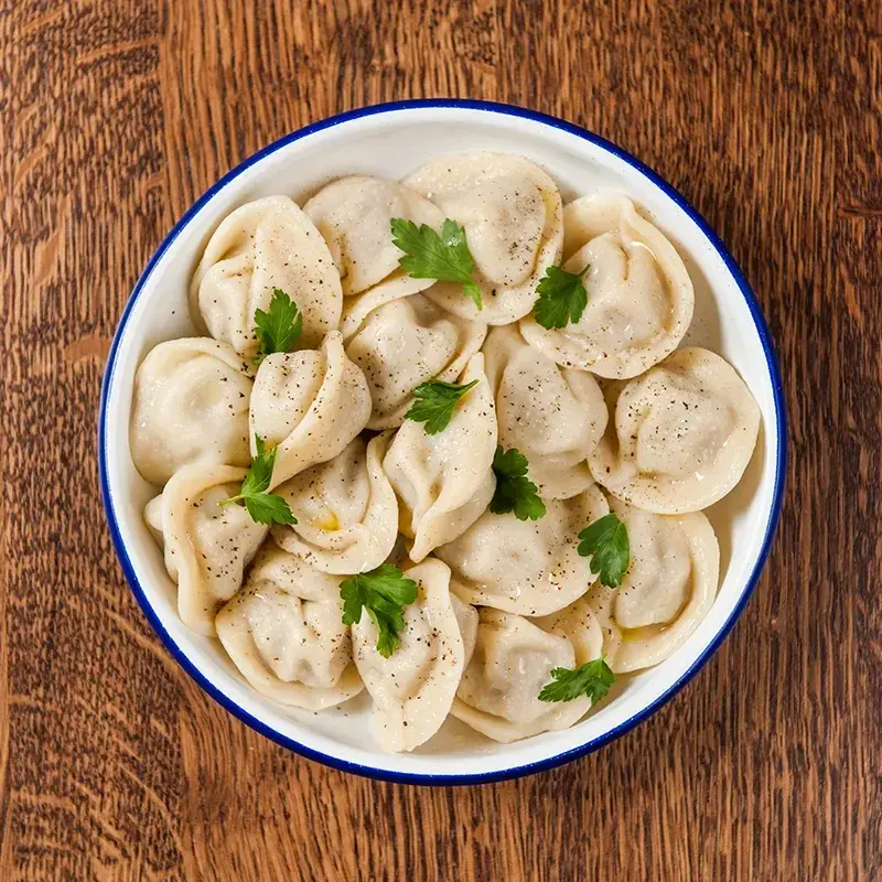 Сибирские пельмени ручной лепки на деревянном столе, рецепт на День Сибири 8 ноября, сибирская кухня.