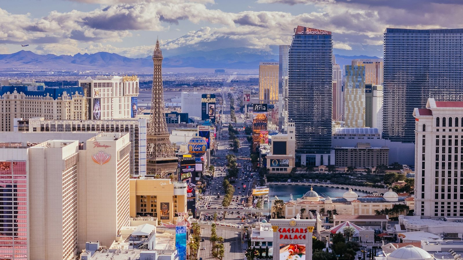 The Las Vegas Strip seen from above, with the Paris hotel's Eiffel Tower replica, the Bellagio fountains lake and desert mountains behind