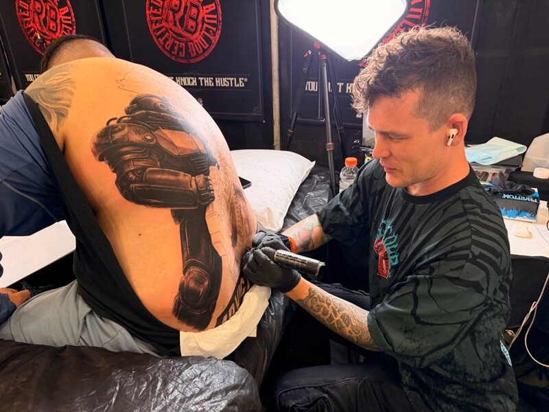 Blog, A Fallout Tattoo at Golden State Tattoo Expo, Carlos showing his in-progress Fallout back tattoo while Rinat works beside him, 617