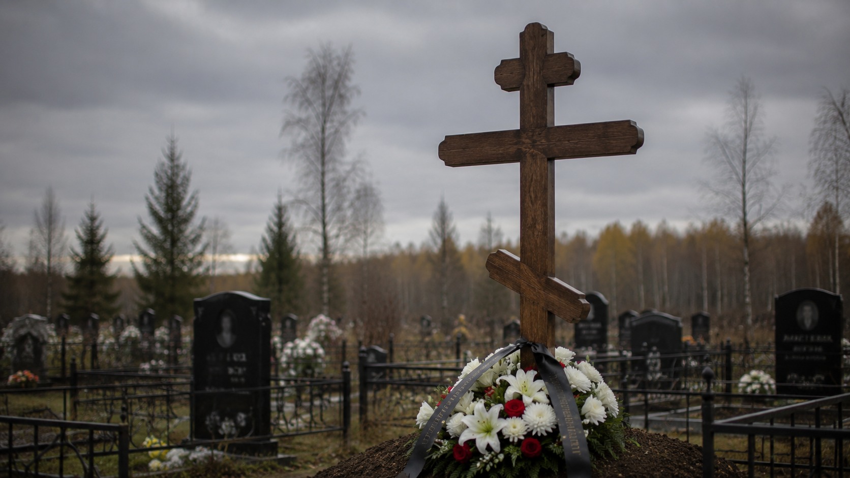 Деревянный крест с цветами и траурной лентой на могиле