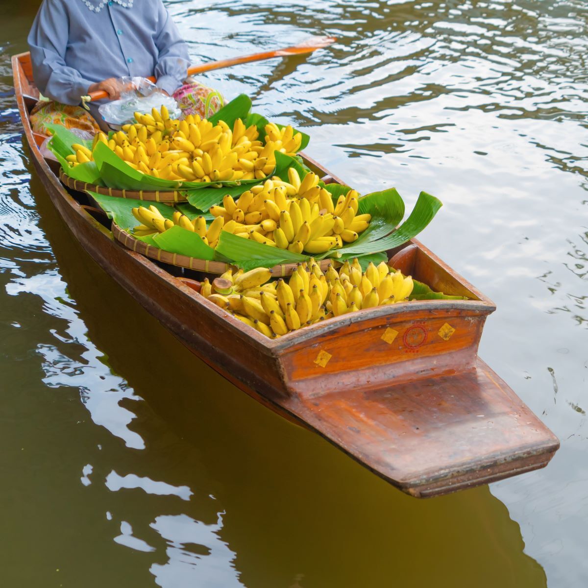 Traditional Thai vendor selling bananas from a boat at Damnoen Saduak Floating Market - Thai Travel Store