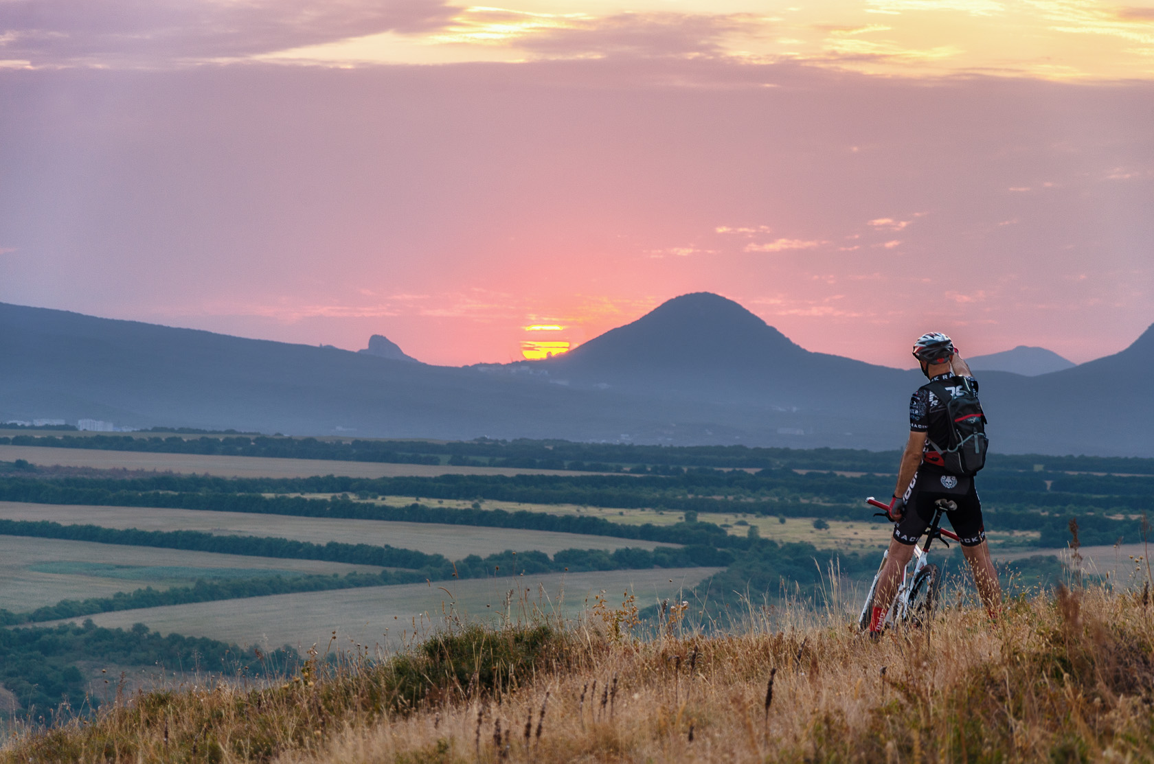 Кавказские Минеральные воды закат над горой Железной и велосипедист на фоне алого неба. Фотограф Севальнев Ян.