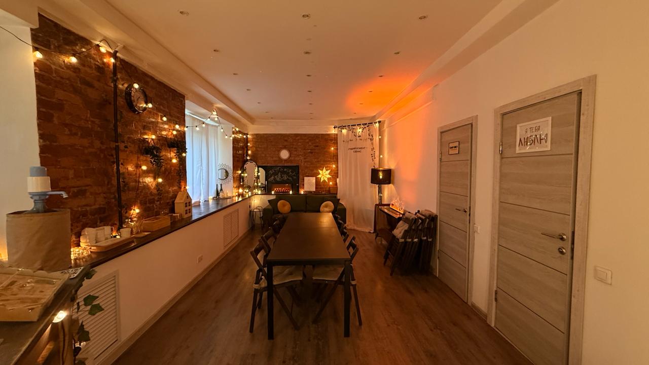 Общий вид зала LOFT: кирпичные стены, большой стол, диван и тёплые гирлянды