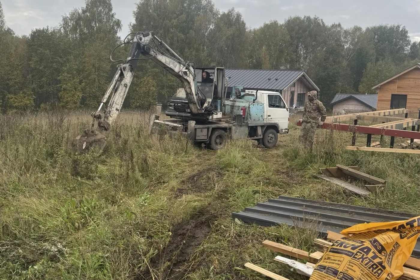 Прокладка траншеи для водоснабжения и мешки эковаты на стройплощадке дома из бруса