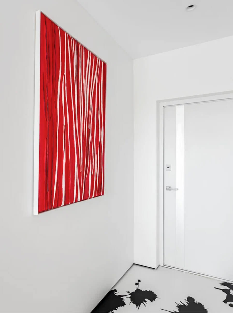 Дизайн интерьера в белых и красных тонах, с рисунком чёрных пятен на полу. Красная рельефная картина на белой стене
