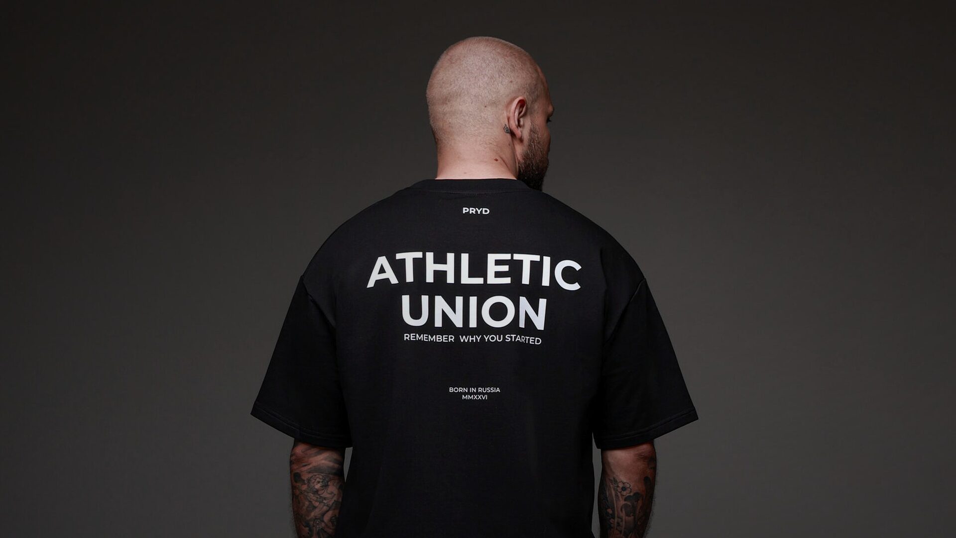 Мужчина со спины в чёрной футболке PRYD с принтом ATHLETIC UNION