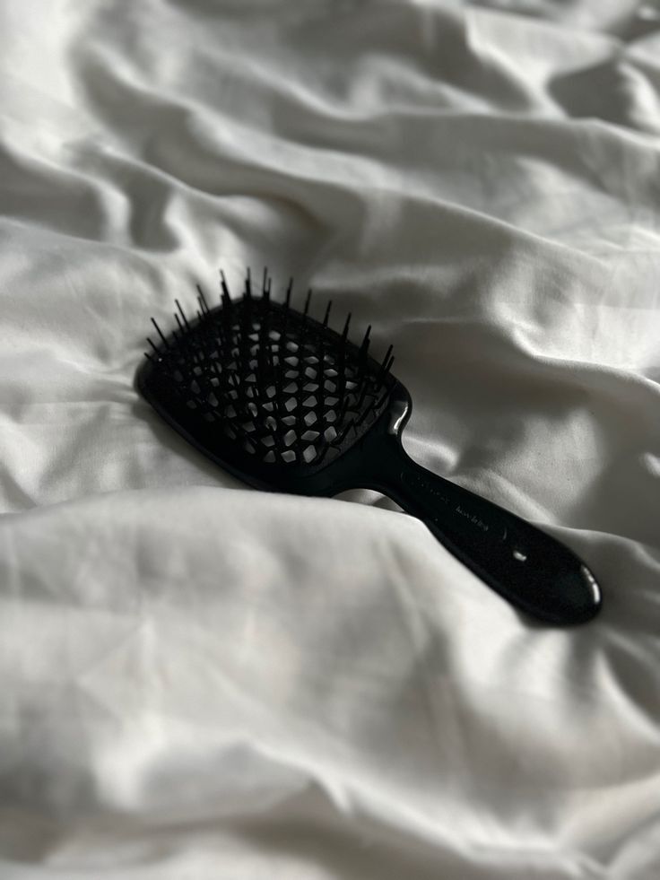 черная расческа на белой простыни