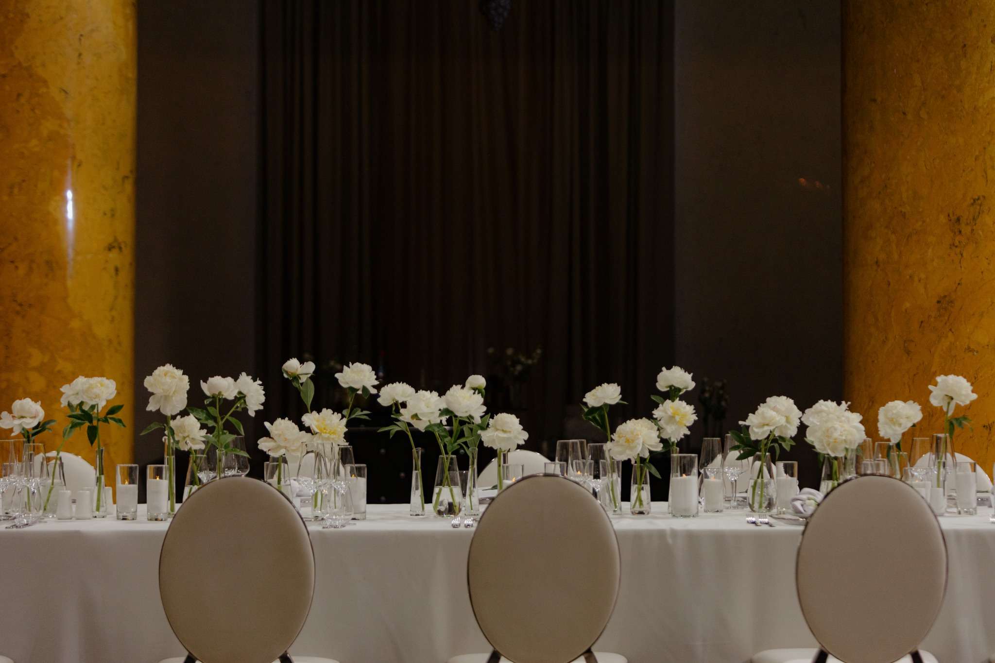 Свадебный банкетный стол с белыми пионами и свечами в историческом зале с мраморными колоннами — элегантная классическая сервировка для премиальной свадьбы в Санкт-Петербурге от Global Wedding &amp; Event.