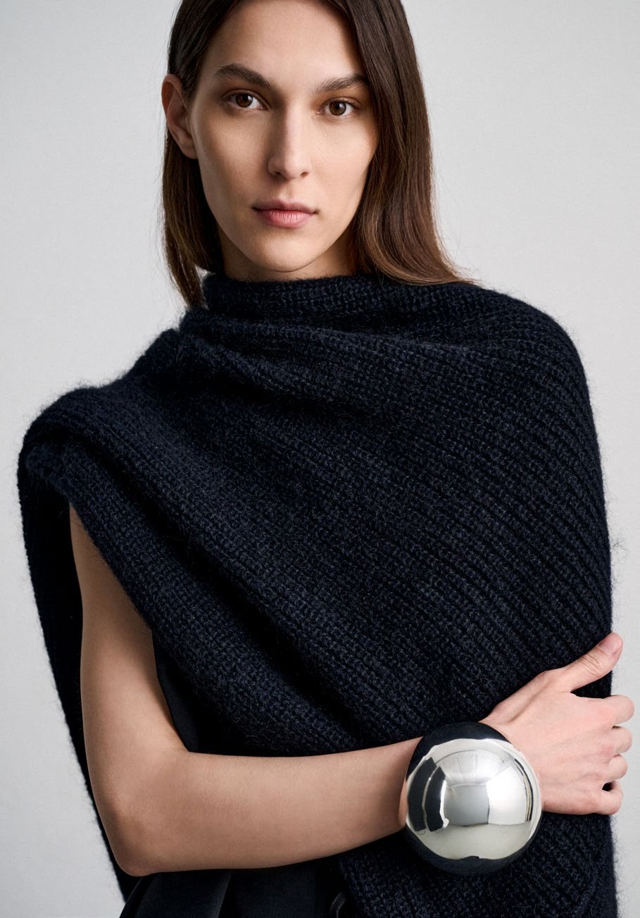 SU: black knitted cape and sculptural bracelet