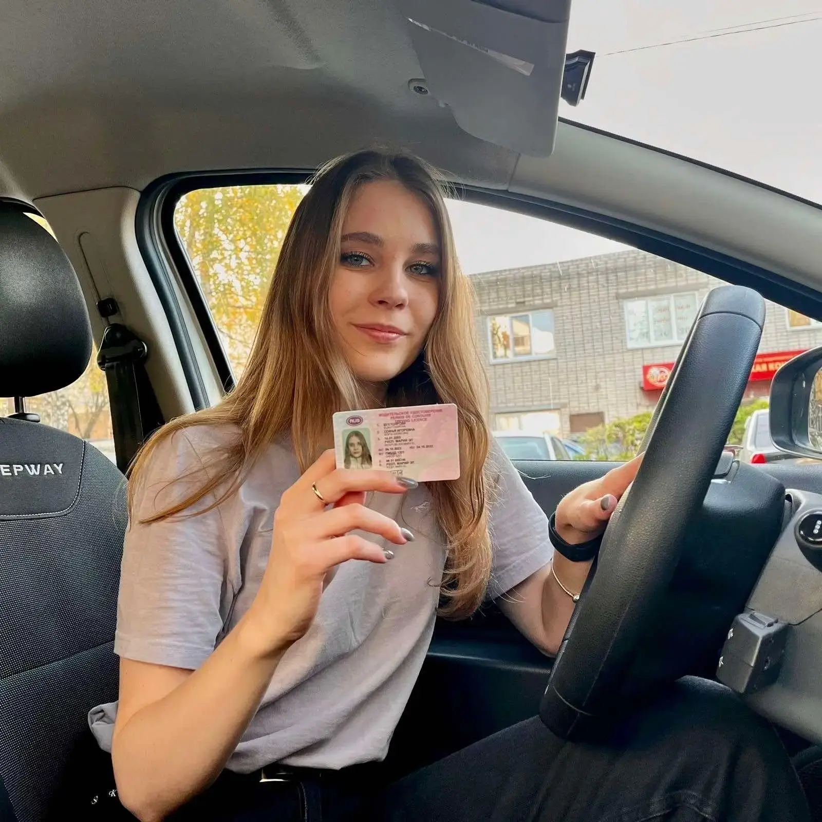 Ученица с правами за рулём после сдачи экзамена в ГИБДД