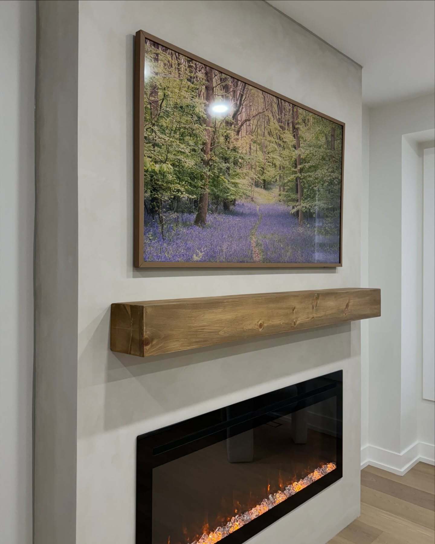 Angled detail of the wood mantel and gray textured fireplace surround.