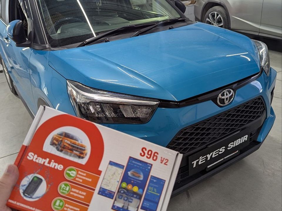 Комплект StarLine S96 V2 в руке на фоне Toyota Raize перед установкой