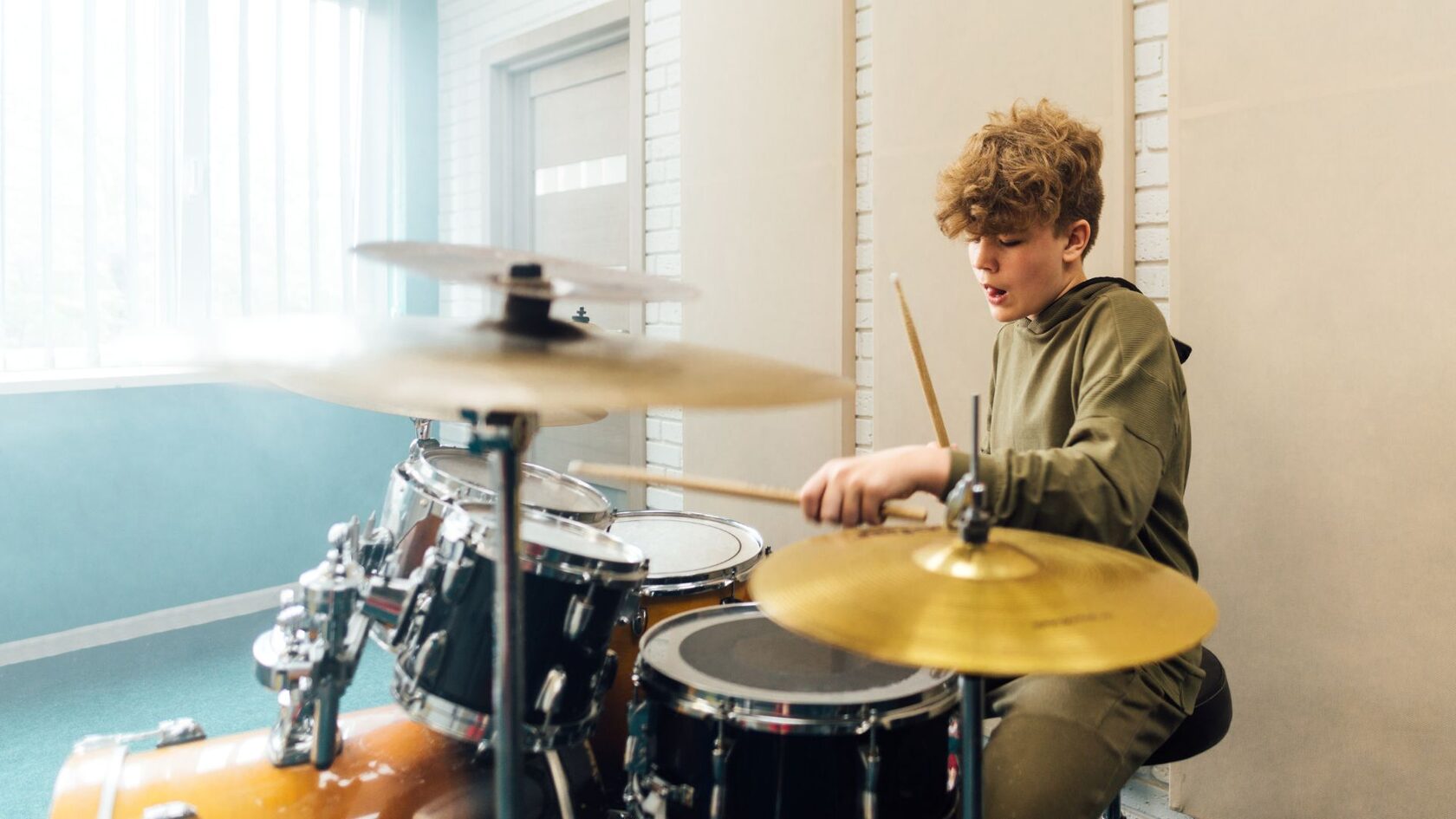 Подросток играет на барабанной установке