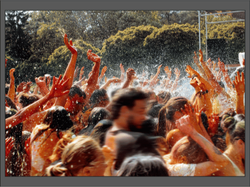Толпа людей на фестивале танцует и радуется под брызги воды.