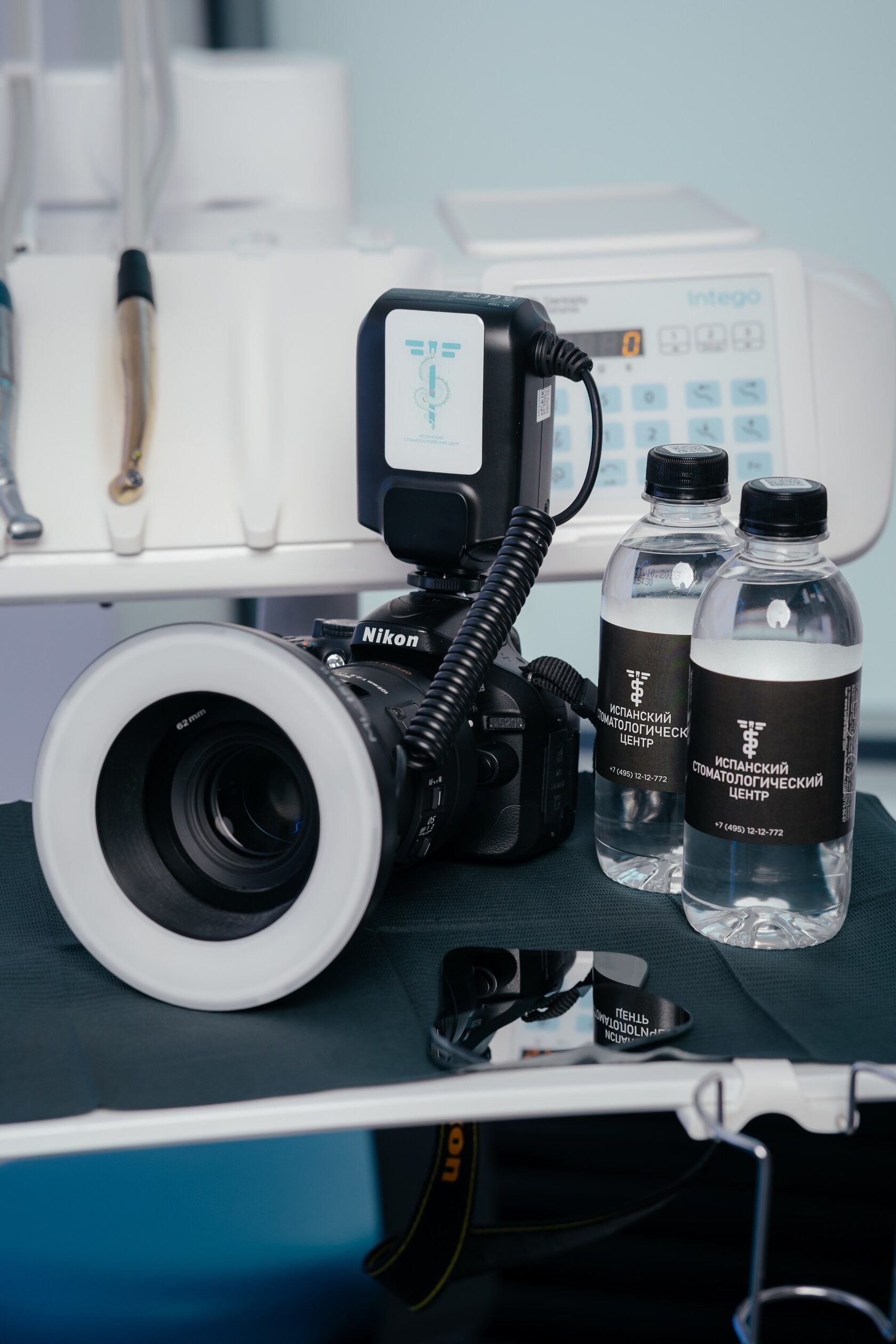 фото на котором стоит фотоаппарат и дву бутылки с водой на которых написано испанский стоматологический центр