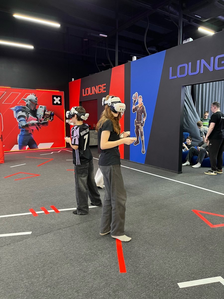 Участники в VR-шлемах с контроллерами рядом с лаунж-зоной Portal VR