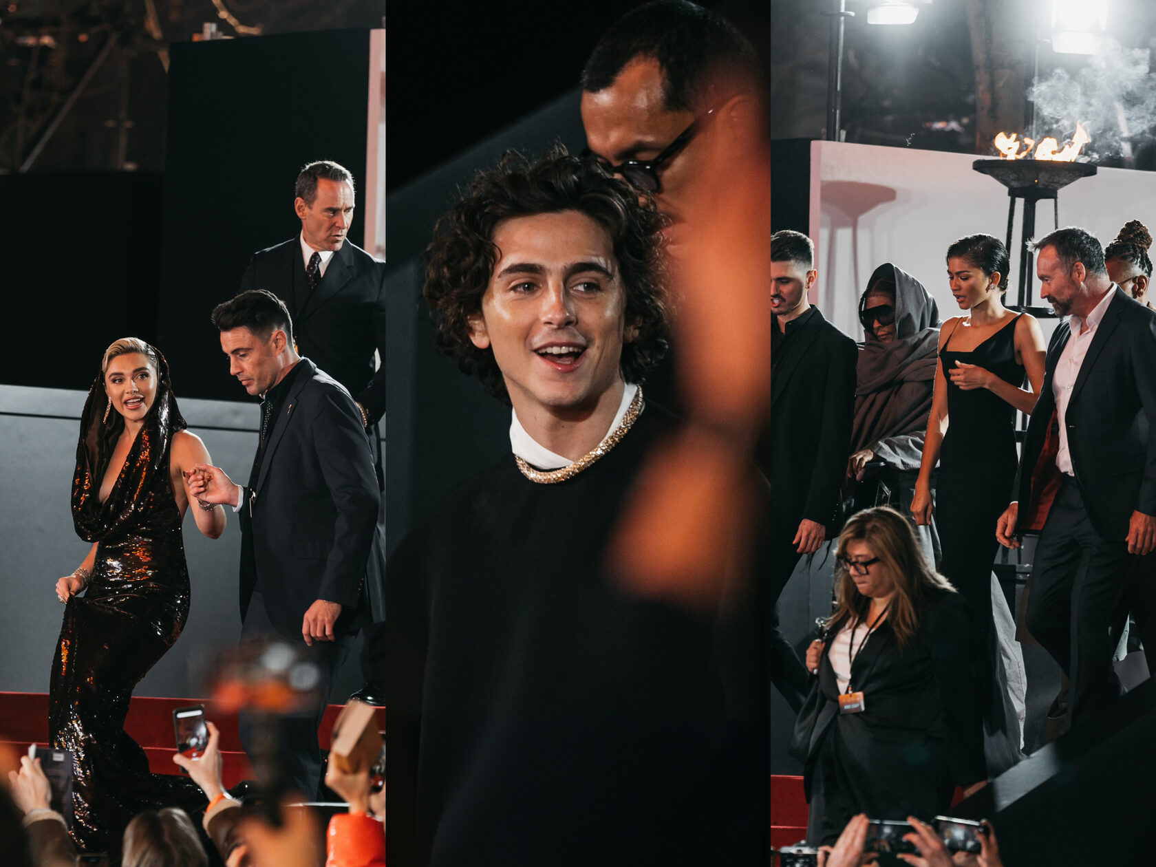 Timothée Chalamet, Florence Pugh, and Zendaya captured in a candid moment while walking the red carpet, with Timothée in the foreground smiling broadly at the fans, Florence in a glittering black gown escorted by a suited gentleman, and Zendaya in an elegant black dress, as they're surrounded by event staff and the warm glow of event lights.