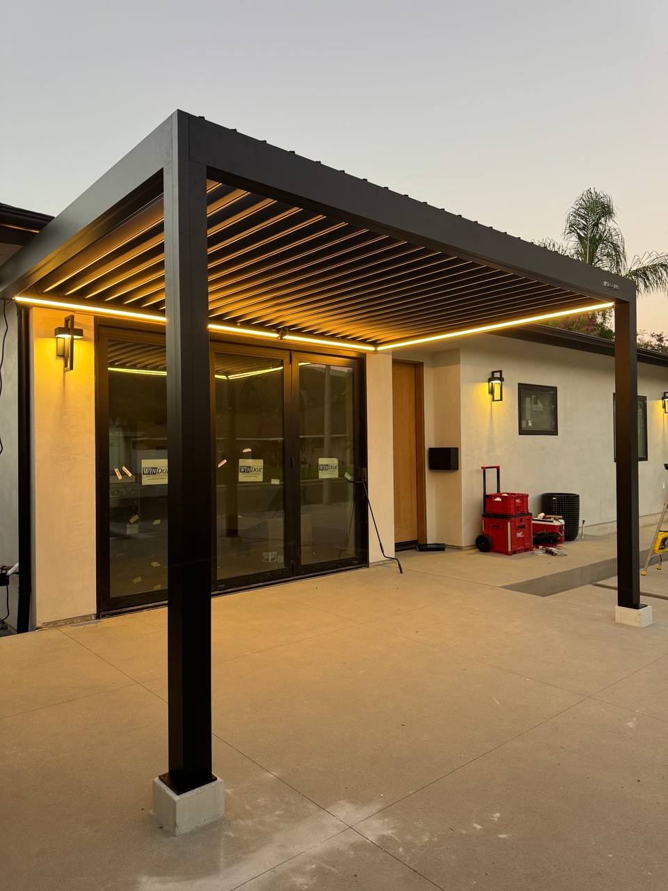 Corner view of the two-post black pergola with integrated lighting switched on.