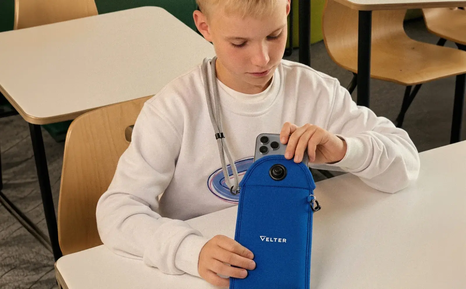 Школьник убирает смартфон в чехол на уроке
