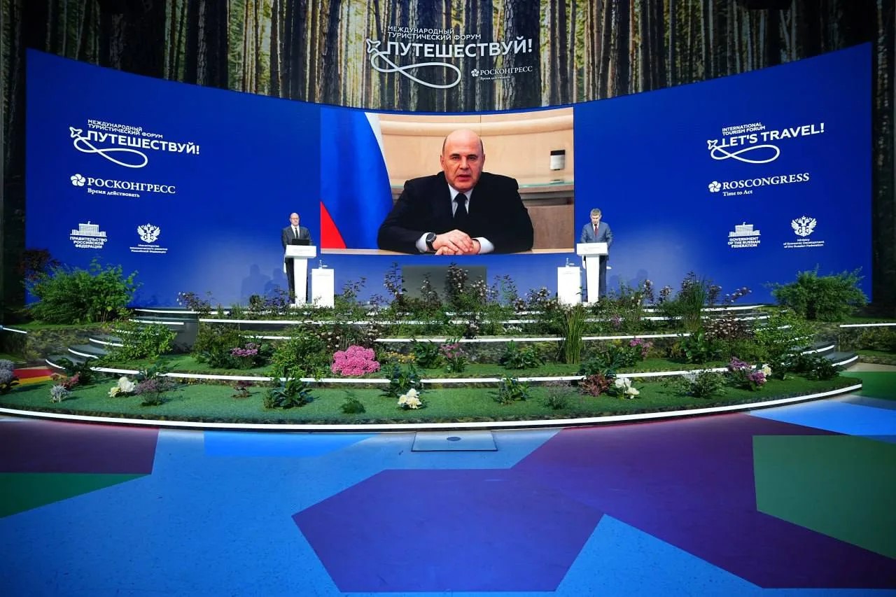 Сцена международного туристического форума «Путешествуй!» на ВДНХ в Москве с выступающими спикерами и большим экраном с видеосвязью.