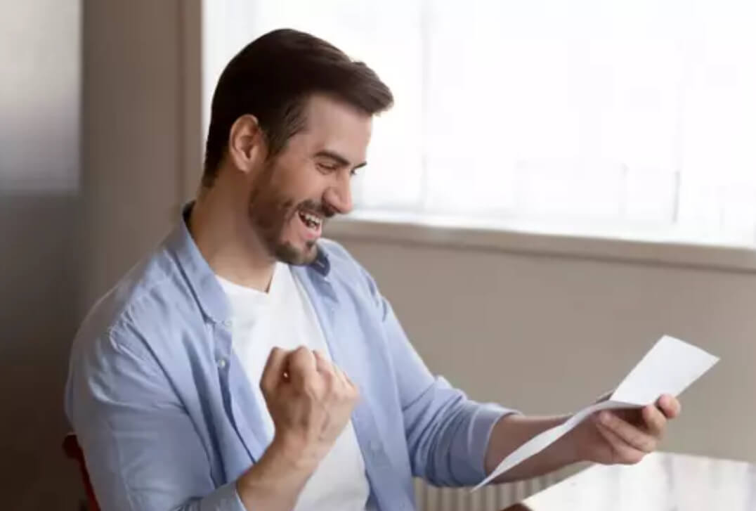 The man, while reading an official document, shows a victory gesture by making a fist with his hand.