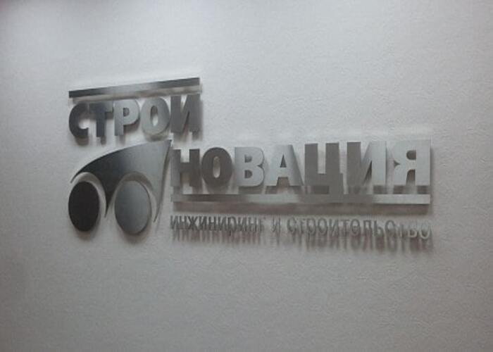 Логотип и надпись СТРОЙНОВАЦИЯ на светлой интерьерной стене